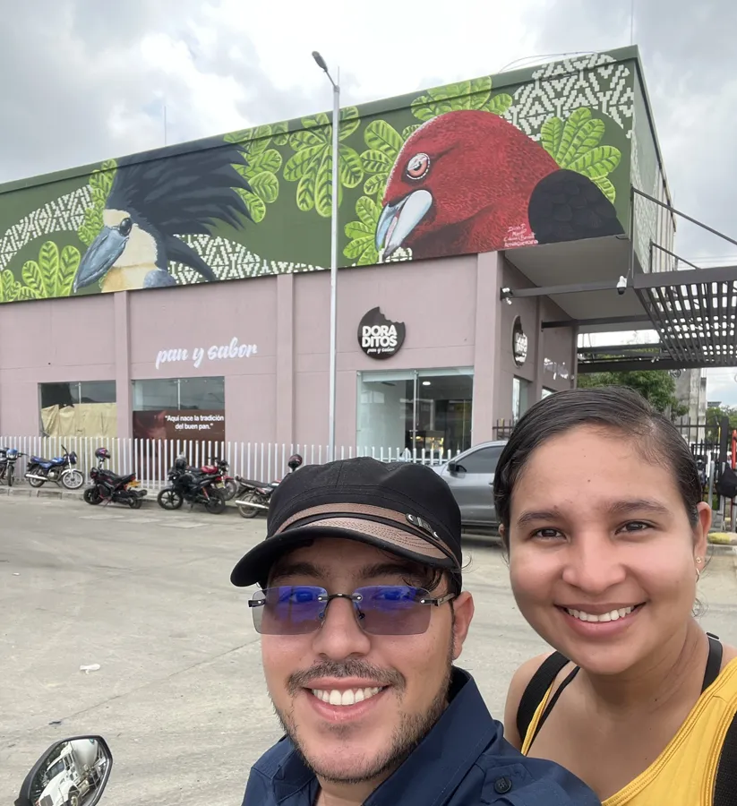 Miguel y Dianis frente a su mural de aves