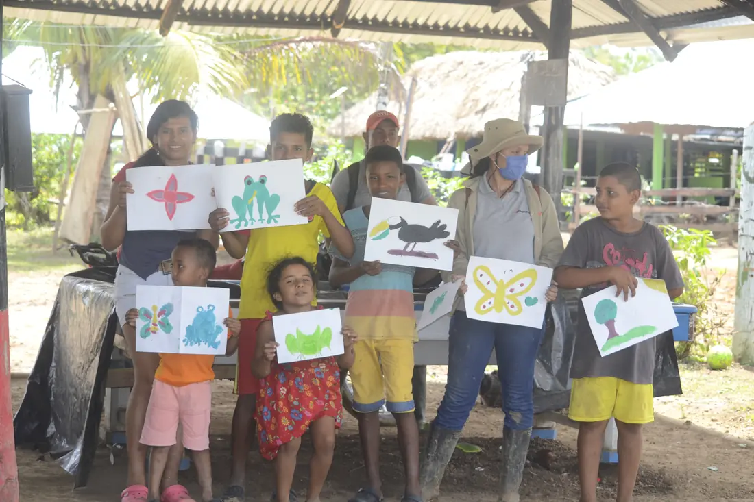 Grupo de niños y adultos muestra sus láminas al final del taller
